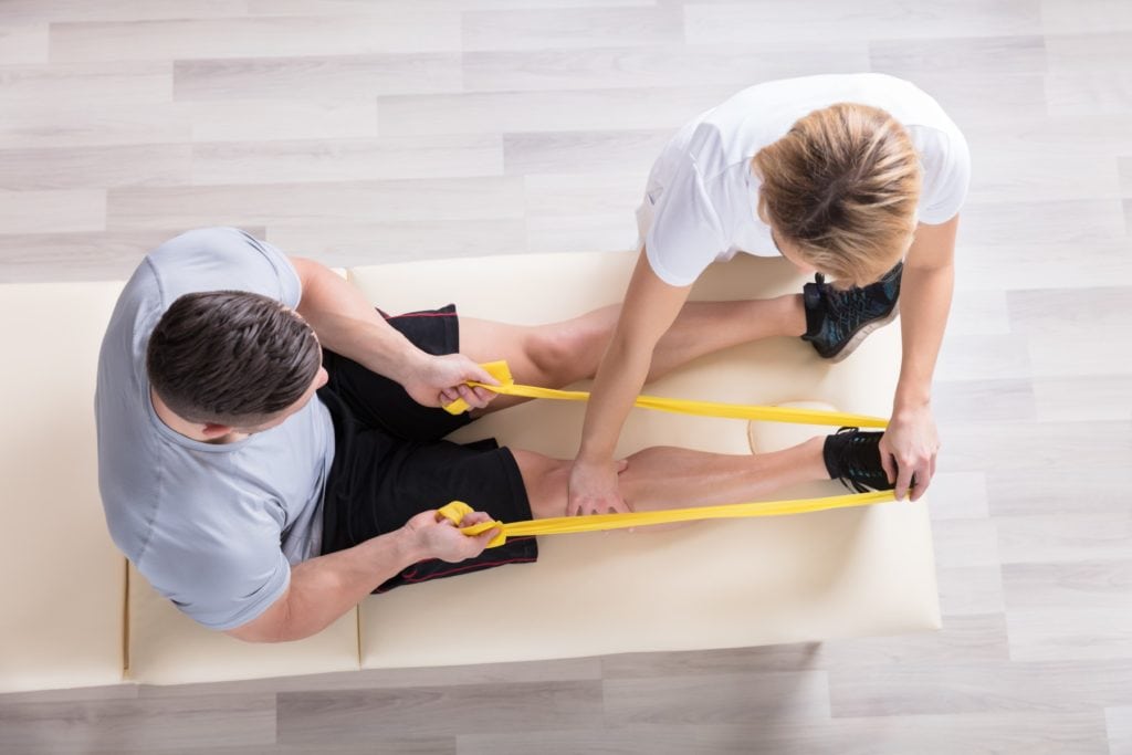Elevated View Of A Female Physiotherapist Giving Exercise Treatment To Man